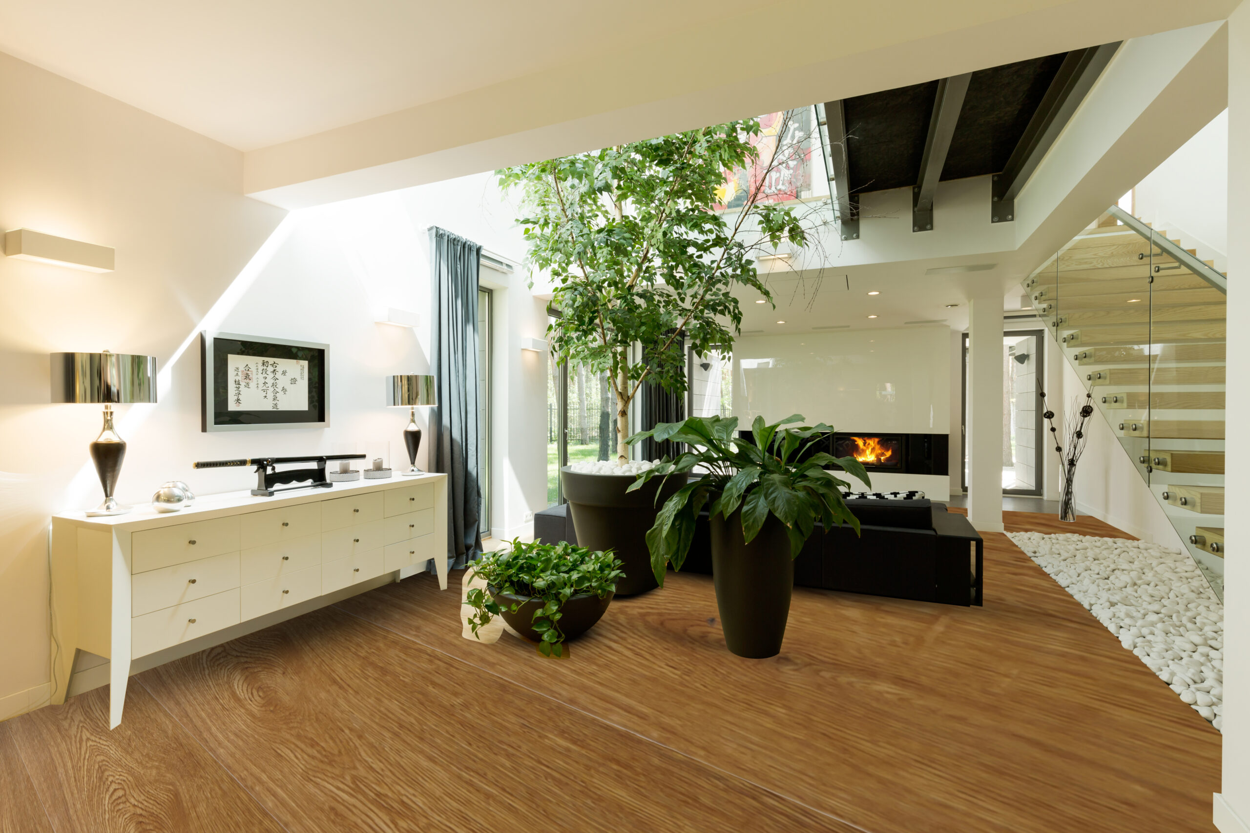 Spacious glass and stone staircase with white commode, potted plants and skylight